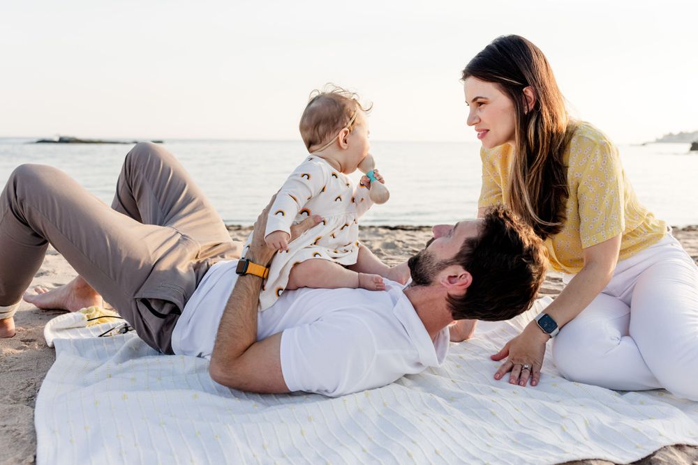 Intimate family portrait session with relaxed poses on white bedding.