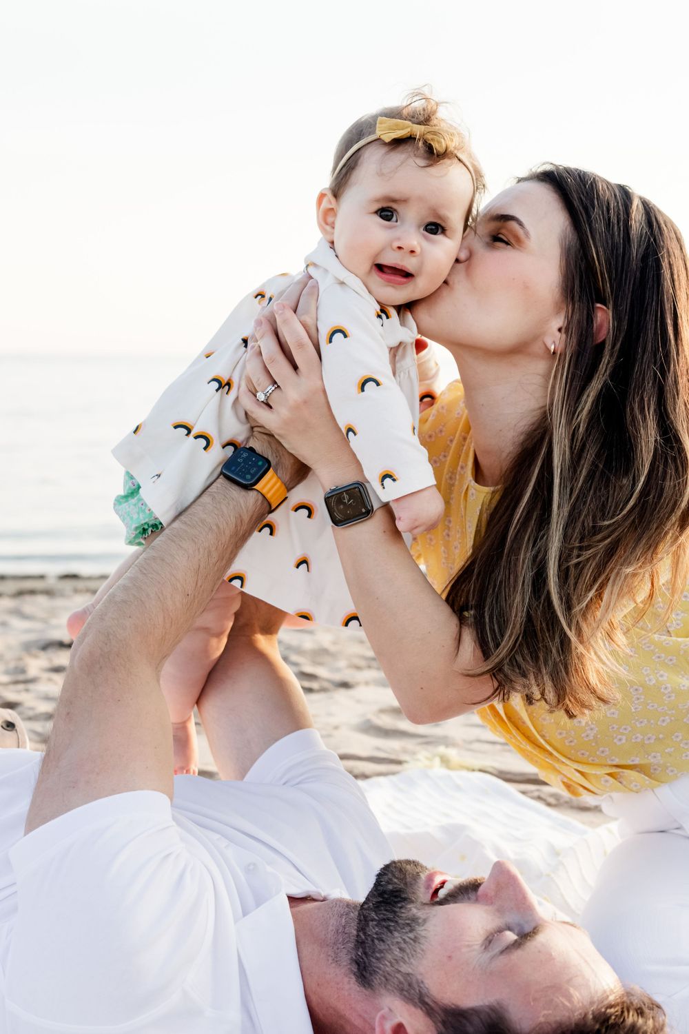 Tender family moments captured against a bright sunset backdrop at the beach.