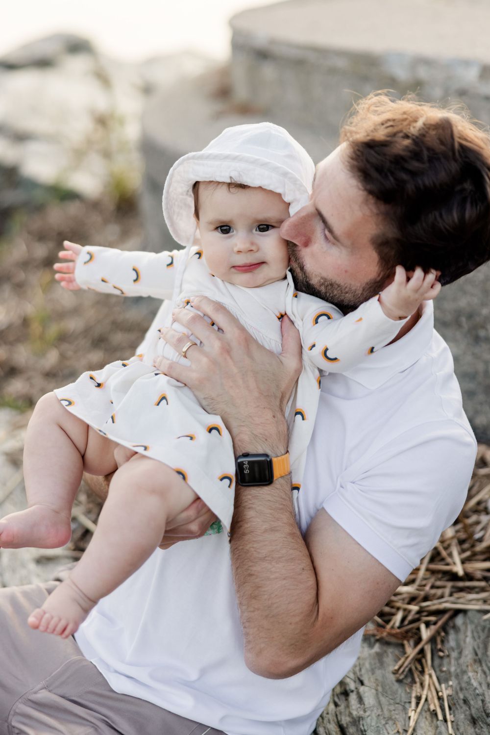 Sweet family interactions captured in white outfits on natural terrain.