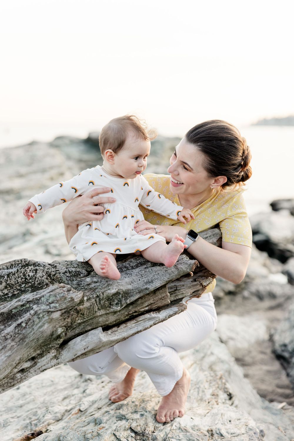 Intimate family moments photographed on coastal rocks during sunset.