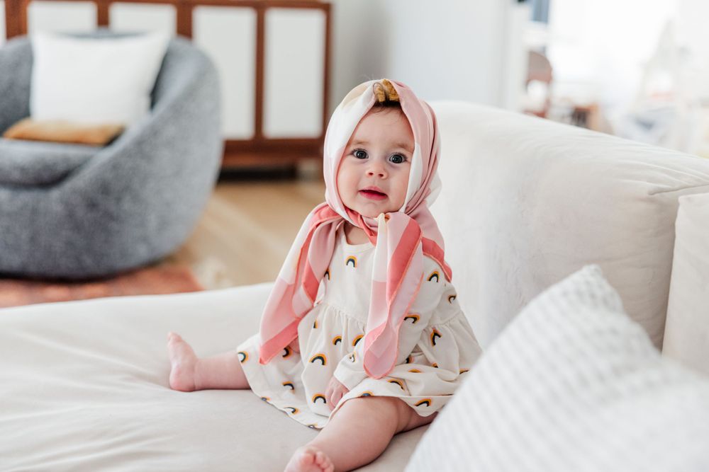 Sweet moments captured on a white bed with soft natural lighting and pink accents.