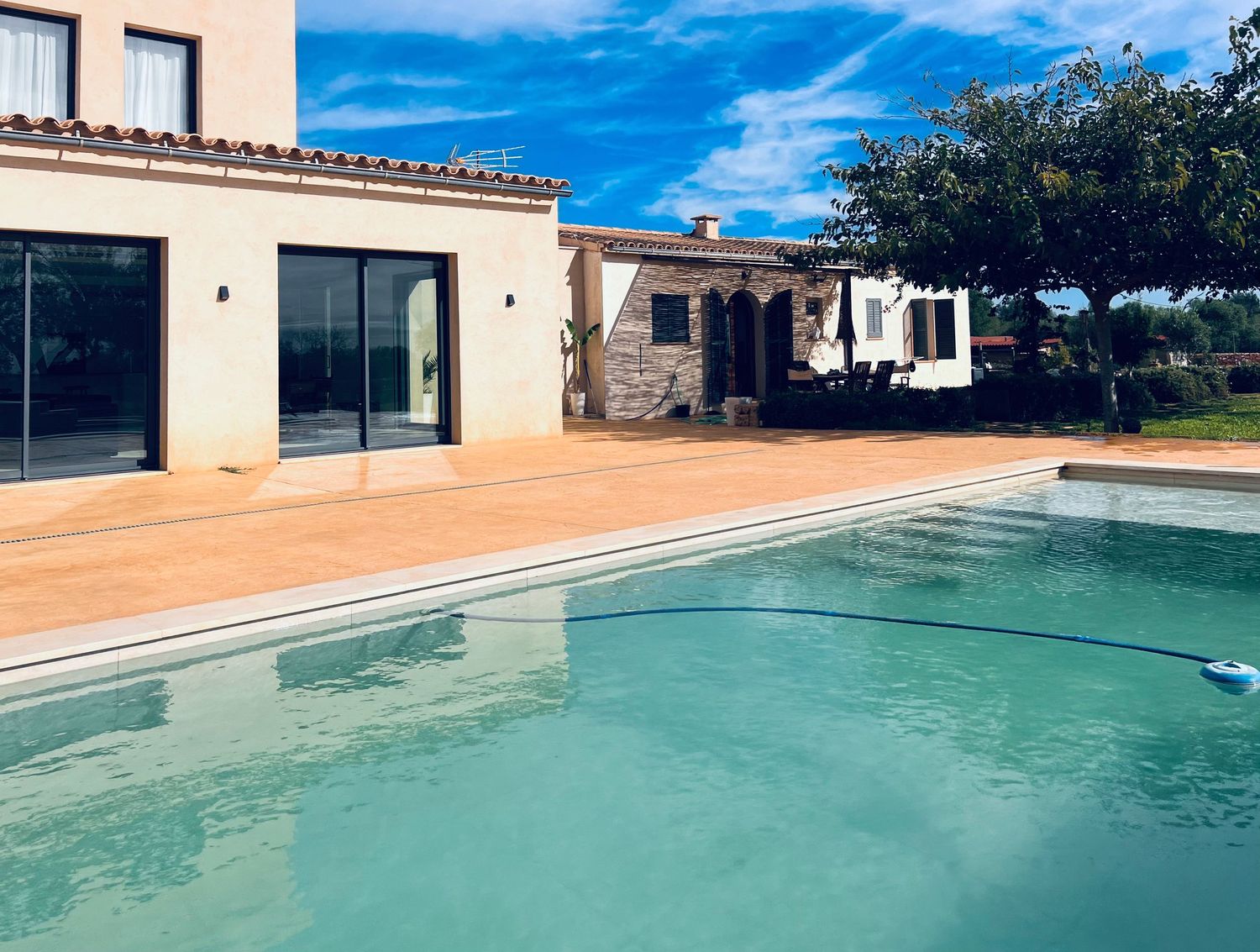 Modern Mediterranean villa with turquoise pool and terra cotta tiled patio.