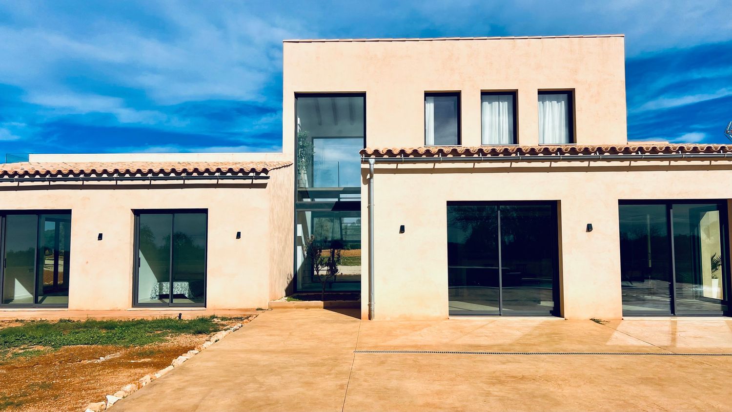 Contemporary beige villa with large glass windows and modern architectural design in a desert setting.