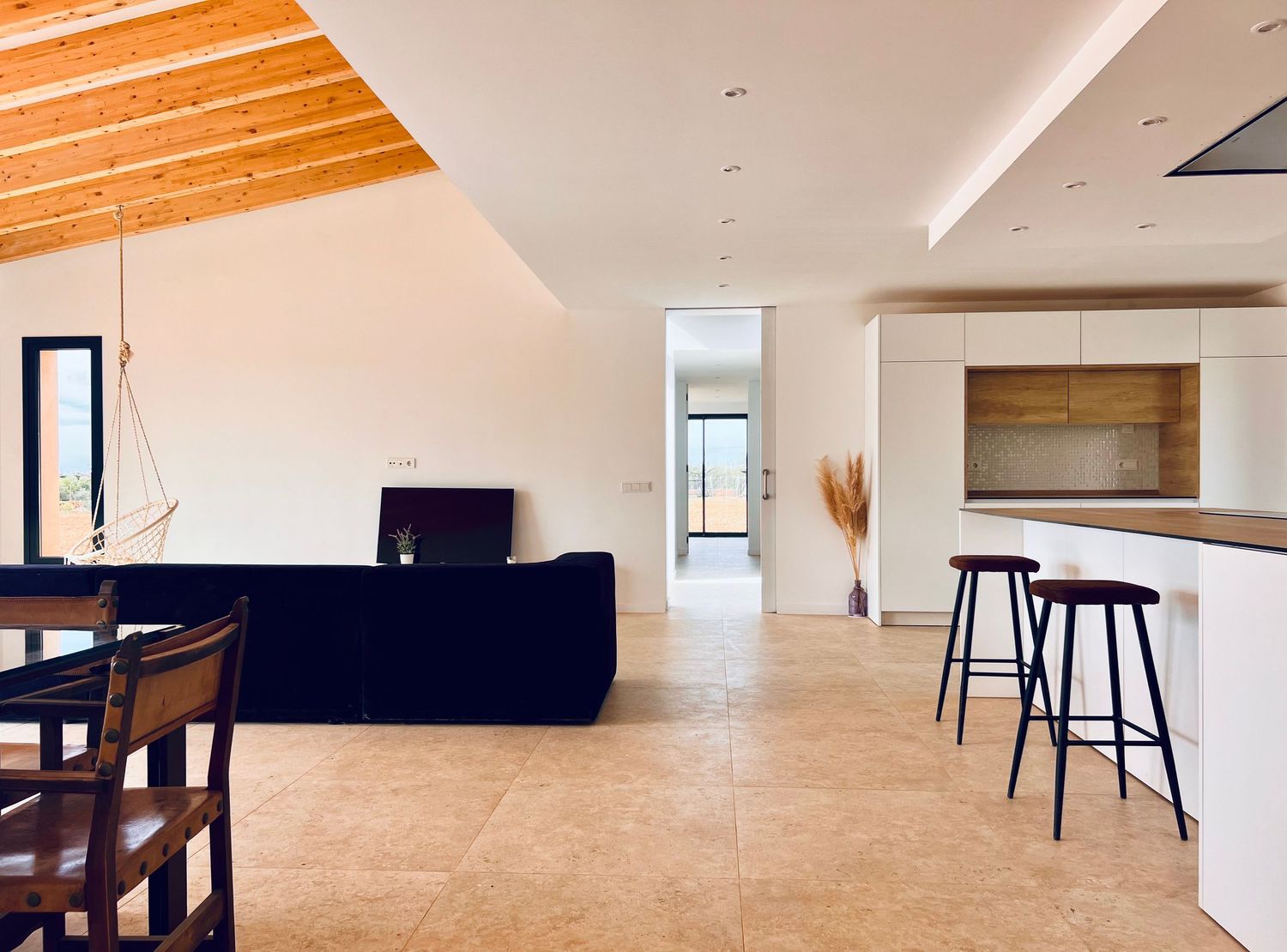 Open concept living and dining area with wooden beams and minimalist furniture.