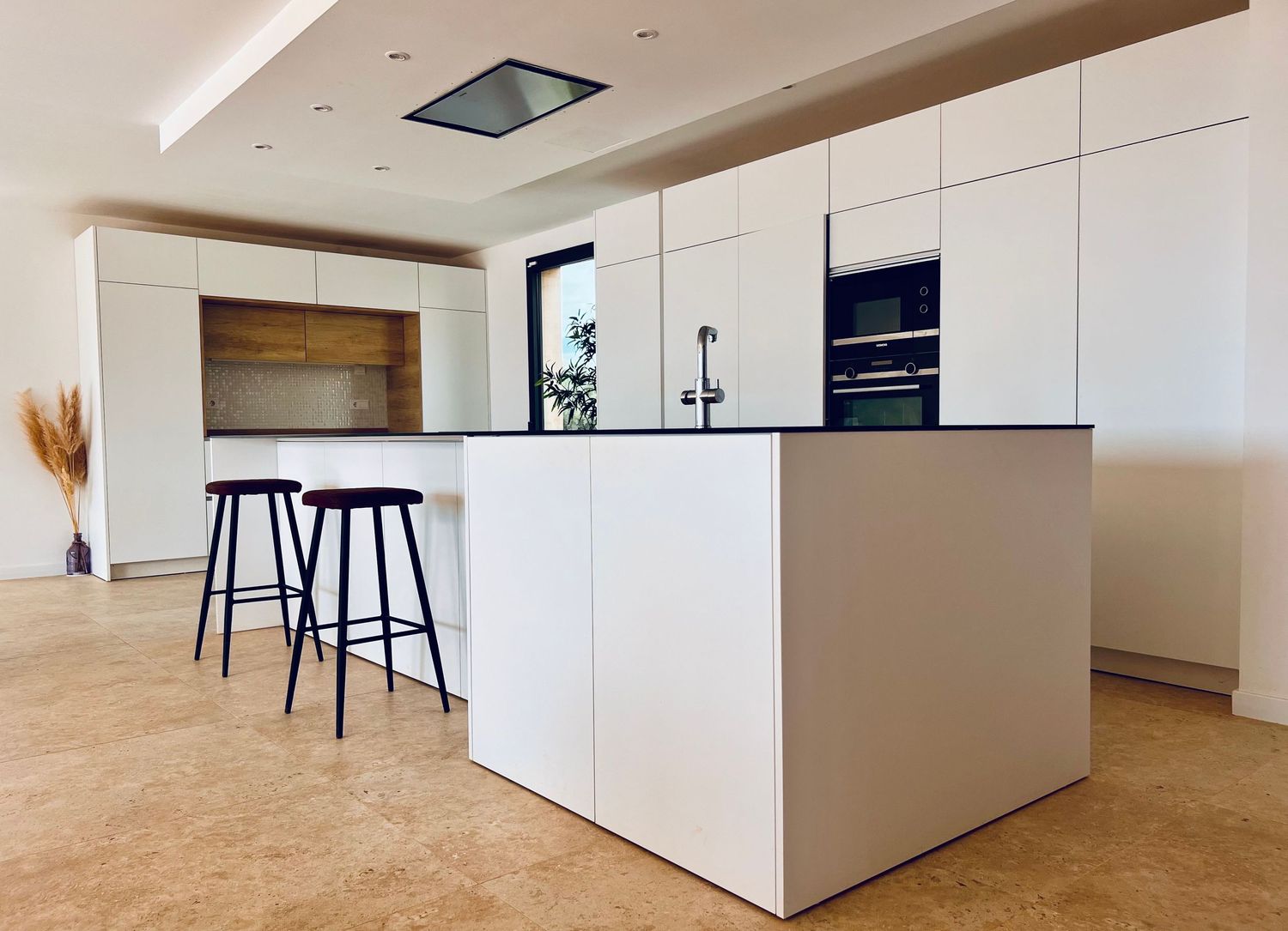 Contemporary white kitchen island with bar stools and sleek cabinet design.