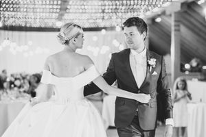 Elegant couple dancing under crystal chandelier at wedding reception.