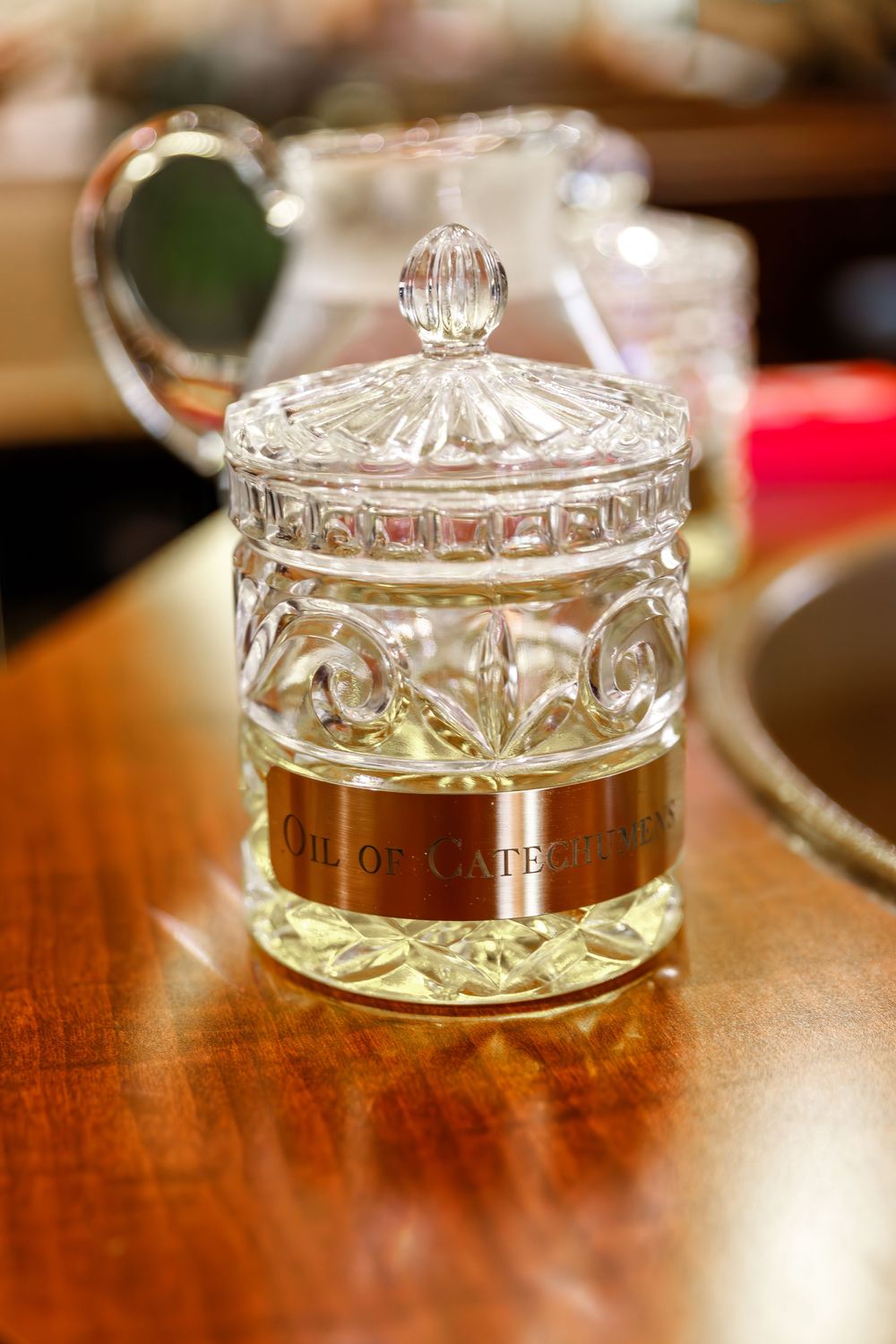 Cut crystal trinket box with antique brass band labeled "MIRROR SAFE" sitting on polished wooden surface.