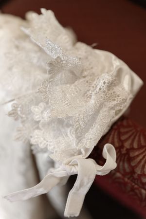 Delicate white lace and ribbon detail from a christening gown or baptismal dress.