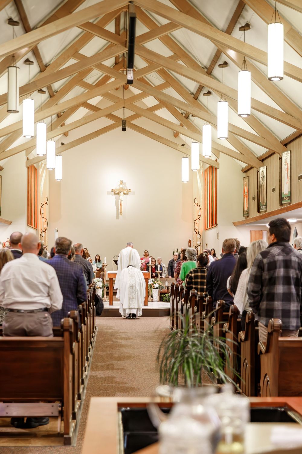 Interior of a church sanctuary with exposed wooden beams and pews filled with people during a service.