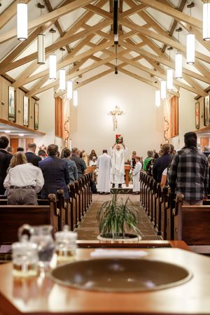 Church interior with wooden beam ceiling and congregation gathered for baptism ceremony.