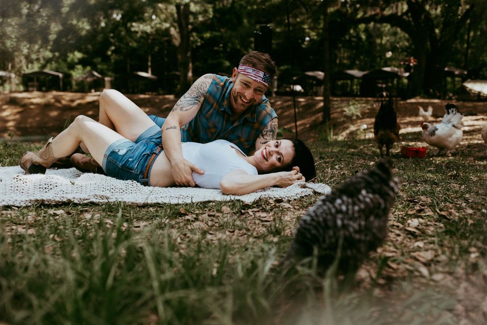 A figure lies on fallen autumn leaves in a wooded area during a moody outdoor photo session.