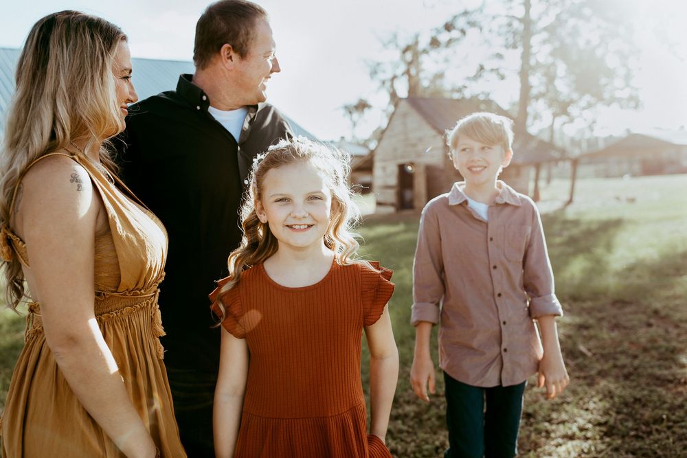 A golden sunset photoshoot of a family in earth-toned clothing standing together in a natural outdoor setting.