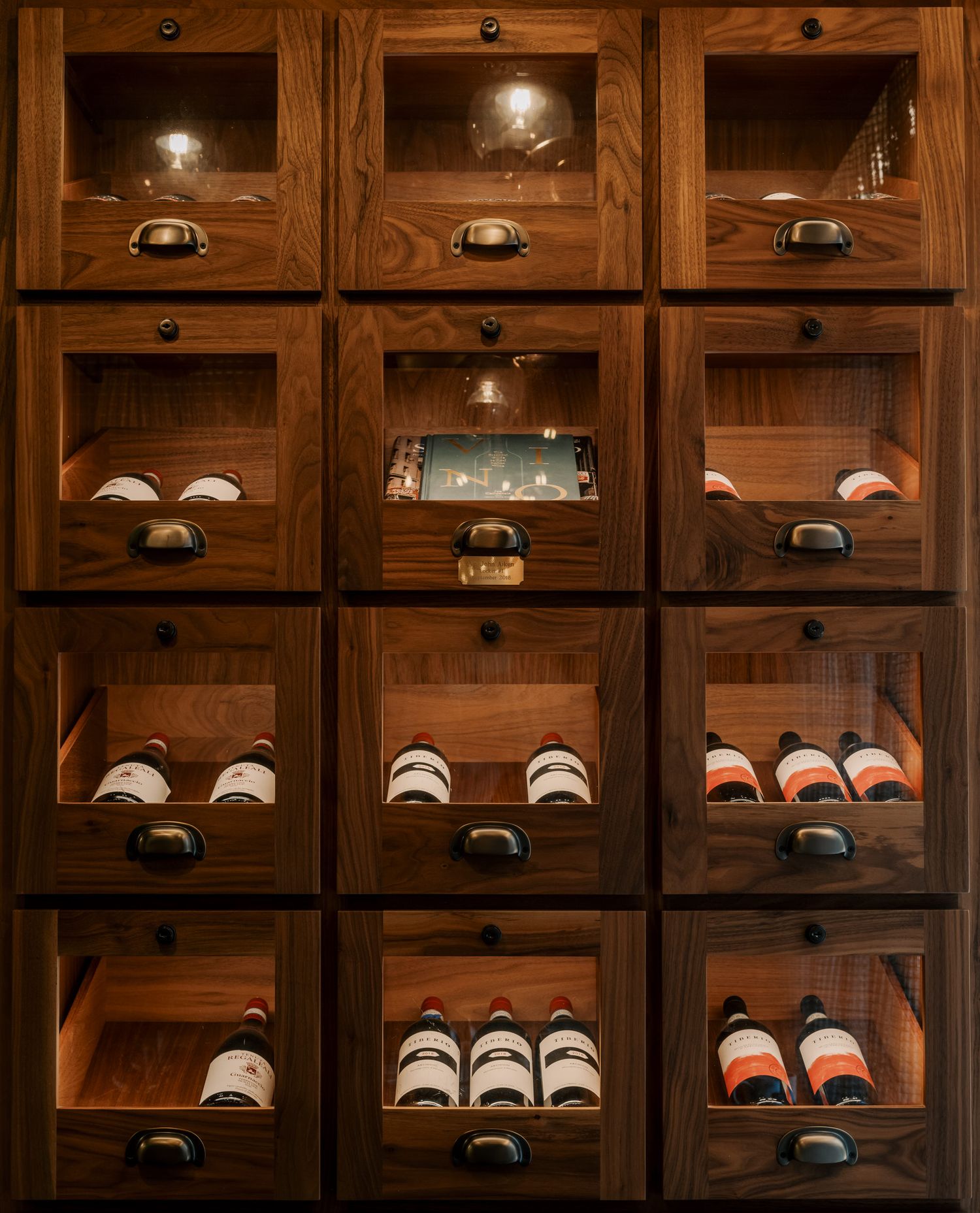 Wooden wine storage cabinet with illuminated individual compartments displaying bottles in organized cubbies.
