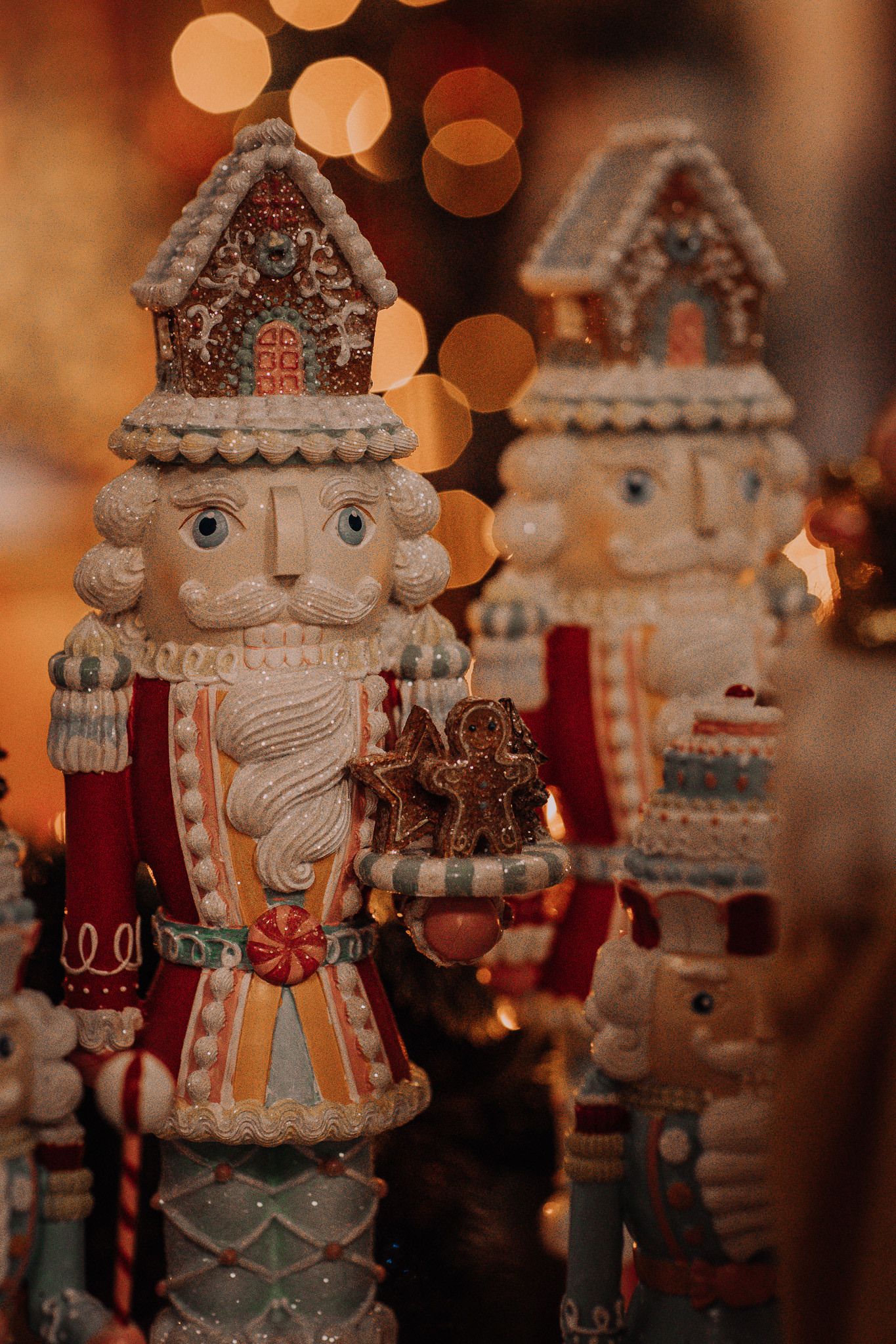 Detailed nutcracker decorations with house-shaped hats in warm holiday lighting.