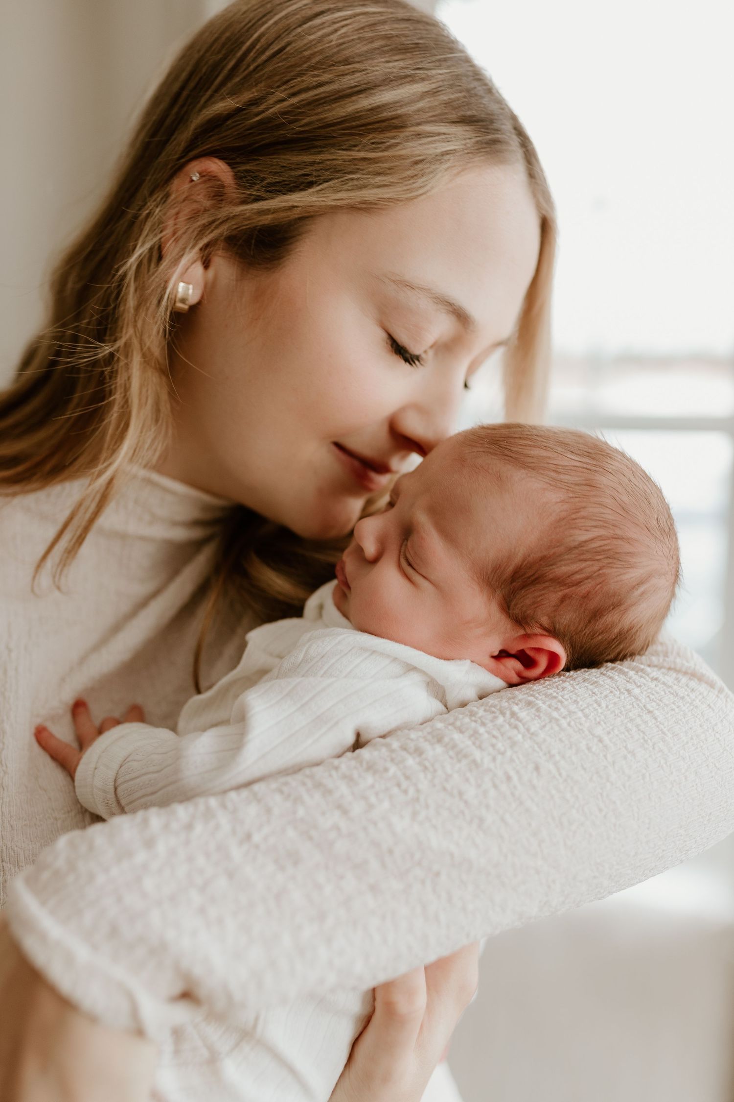 new mom smelling the new baby scent of her newborn daughter