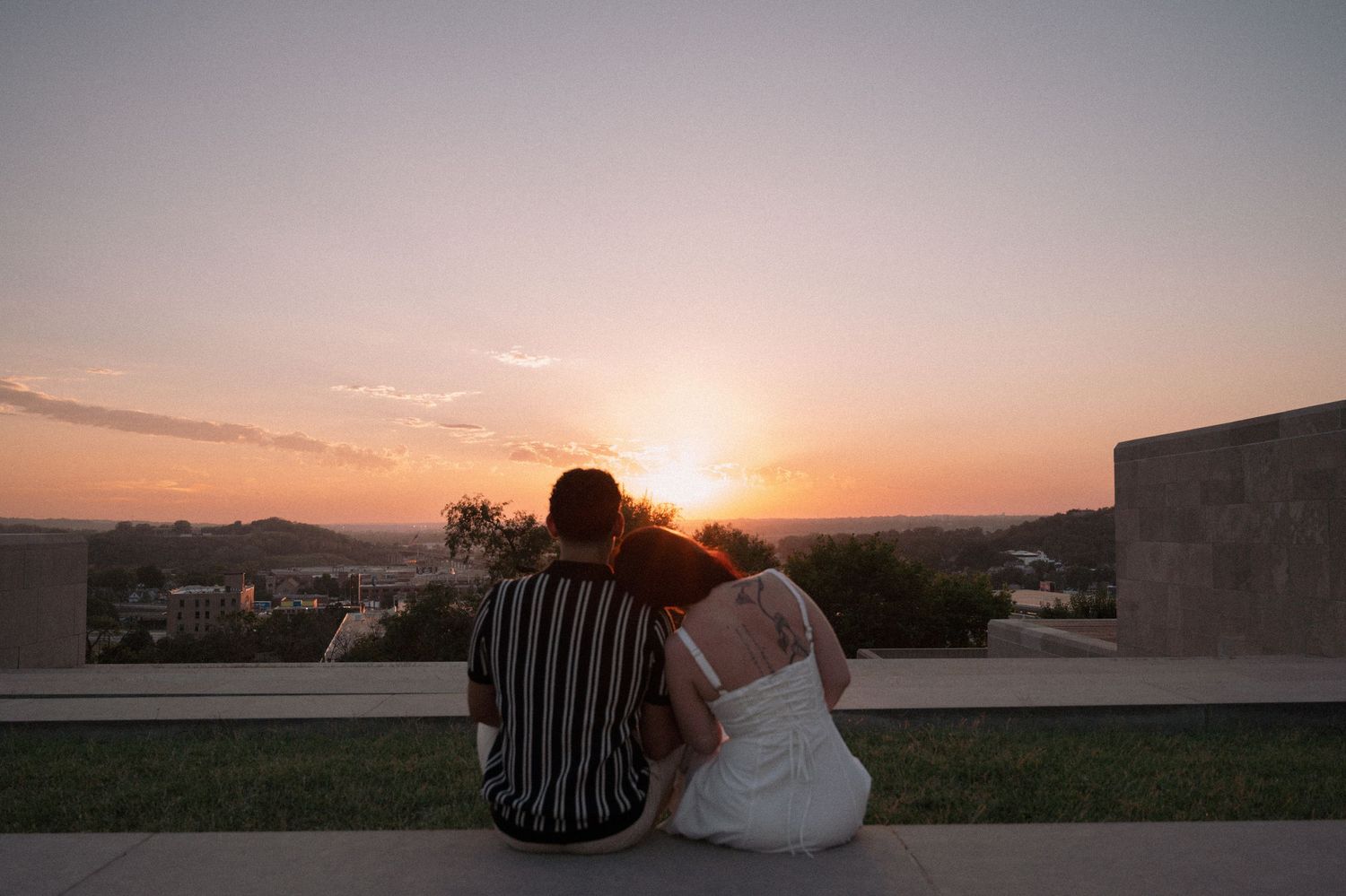 young man and women lean on each other looking off into a kansas city sunset