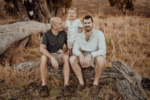 A casual family portrait on a fallen log with trees in the background.