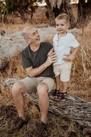 A candid outdoor family moment shared on a fallen tree trunk.