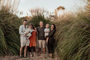 Family portrait among tall grasses during sunset.