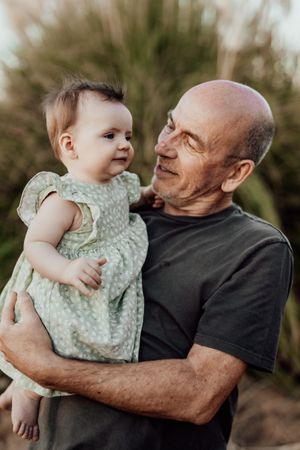 A heartwarming moment between a baby in a polka dot dress and an adult against a natural backdrop.