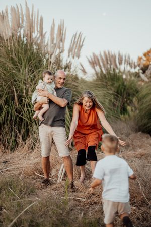 A casual family outdoor photoshoot with tall pampas grass in the background.