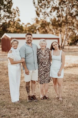 Family wearing coordinated outfits poses together in a field during golden hour sunset.