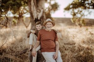 Two people pose for a warm sepia portrait outdoors in natural lighting.