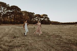 People walking through a serene field at sunset with trees in the background.