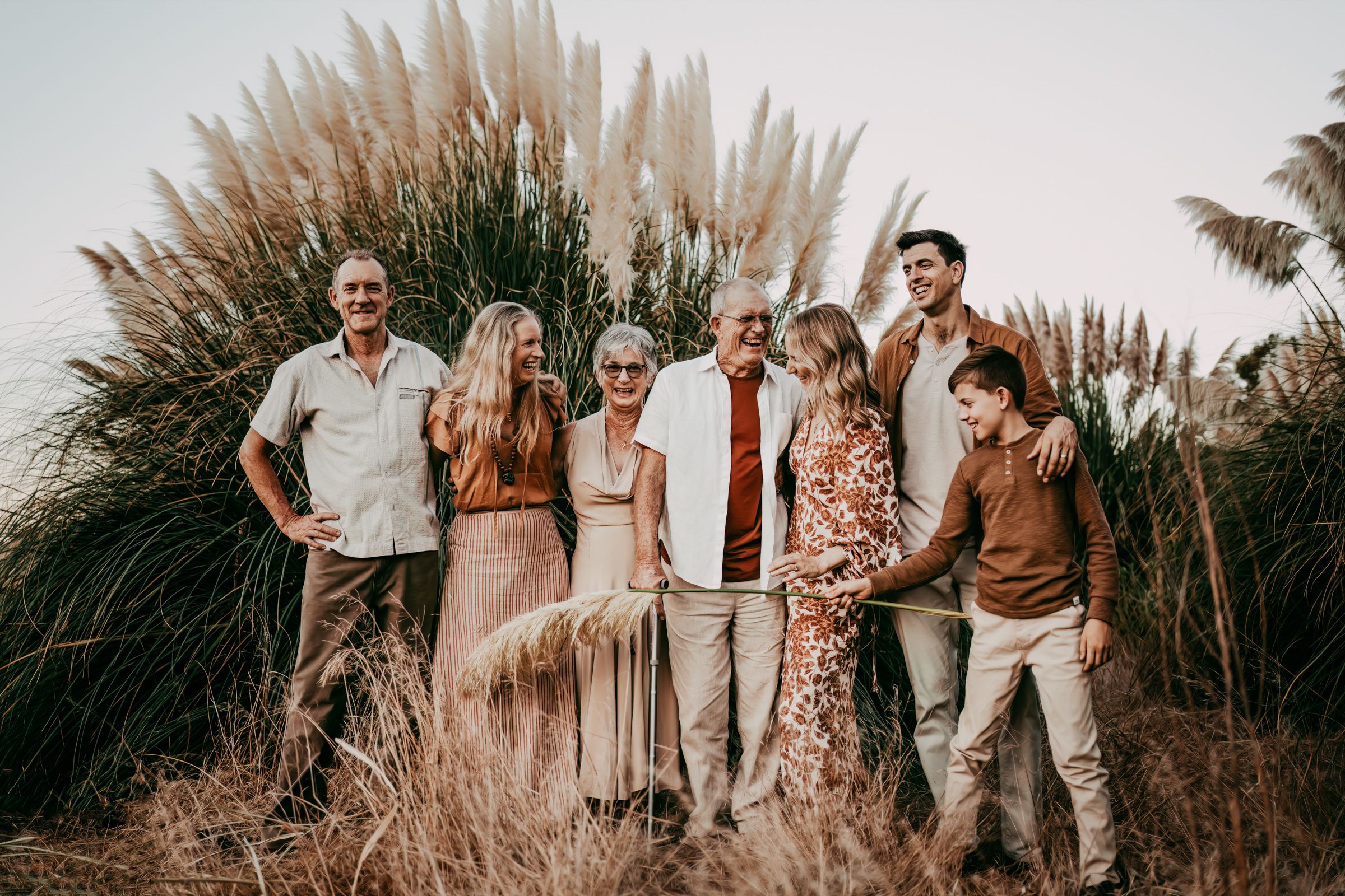 Group portrait session in front of tall pampas grass during golden hour.