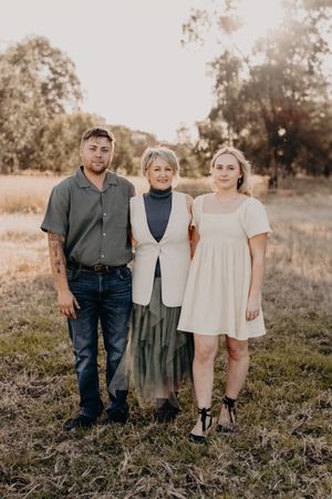 Natural family portrait in a field with warm sunset lighting.