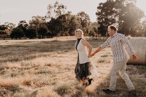 Candid moment captured of a pair enjoying laughter and movement in a sunlit field.