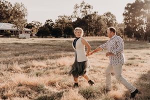 Playful interaction between two people during an outdoor photoshoot in warm evening light.