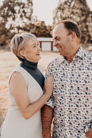 Happy couple sharing a candid laughing moment together in warm sepia tones outdoors.