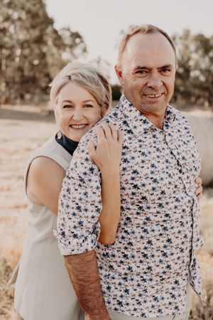 Couple shares joyful moment together during outdoor portrait session in warm lighting.