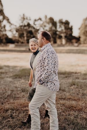 Candid moment of couple laughing together in a rural field setting at sunset.