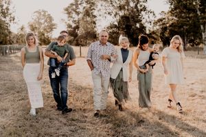 Family members walking in line through rustic field during sunset photo session.