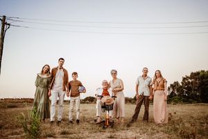 Family photo session in a rustic outdoor field at sunset with warm lighting.