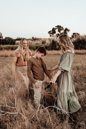 Group walking through tall grass in coordinated neutral outfits during golden hour photo session.