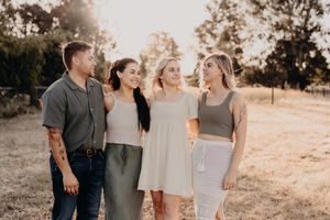 Family wearing coordinated neutral tones poses together in an outdoor setting.