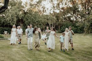 Large family group walking together on green lawn surrounded by trees in a relaxed outdoor setting.