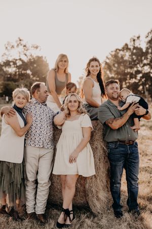 Group photo session with coordinated outfits against rustic hay bale backdrop.