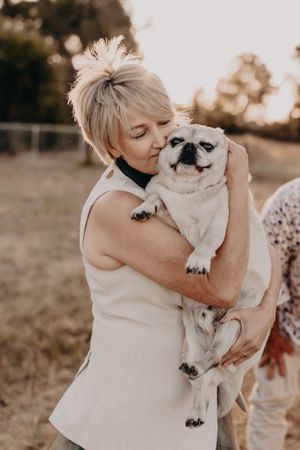 Tender moment captured between a white dog and someone in a sleeveless top during golden hour.