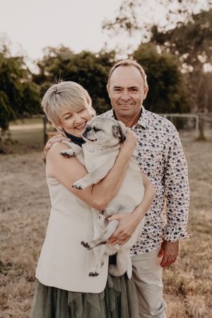 Family outdoor photoshoot with a white fluffy dog in a natural setting during sunset.