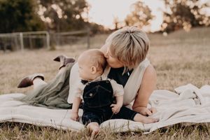 A casual family photoshoot series on a white blanket in a grassy field at sunset.