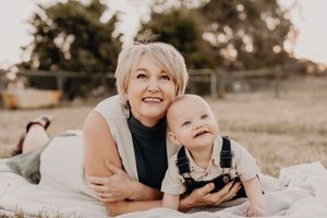 Sweet candid moments between mother and child lying on a blanket in field.