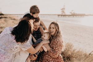Family members share a playful moment together during beach photoshoot.
