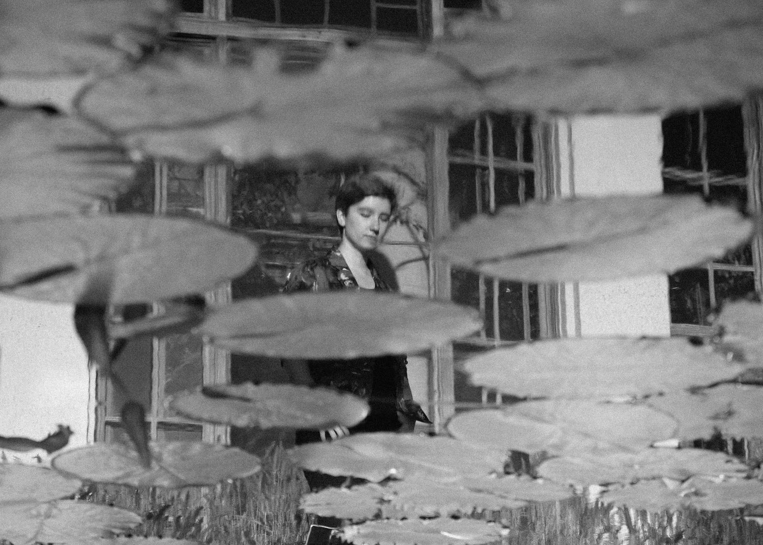 reflection of a girl in a pond with lilly pads