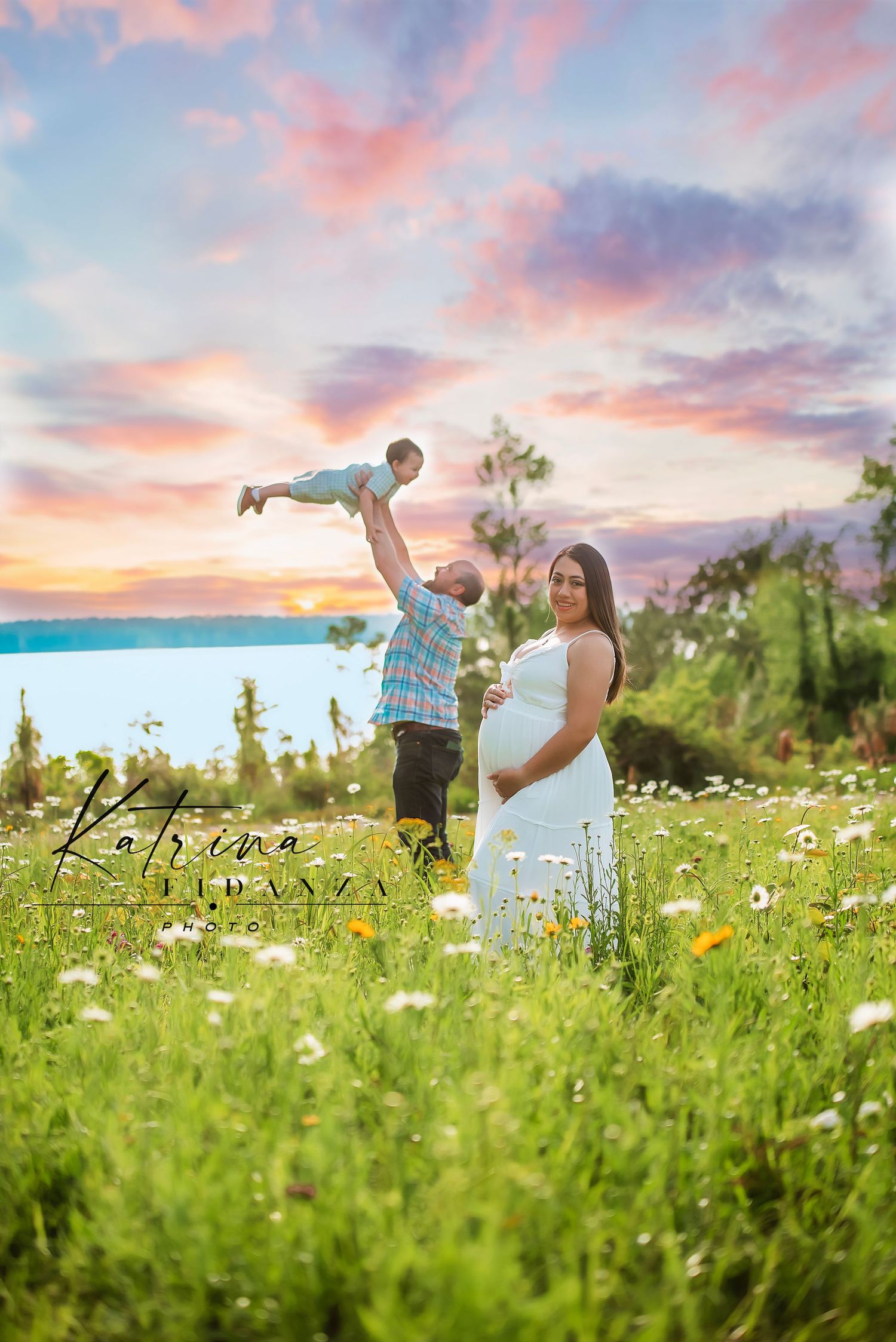 Couple playing in a flower field during sunset with pink and purple sky.