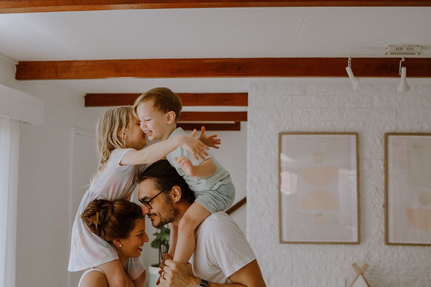 Playful family moment with children and parents beneath wooden ceiling beams.