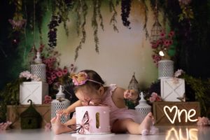 Dreamy floral cake smash setup with hanging wisteria and elegant white decorations.